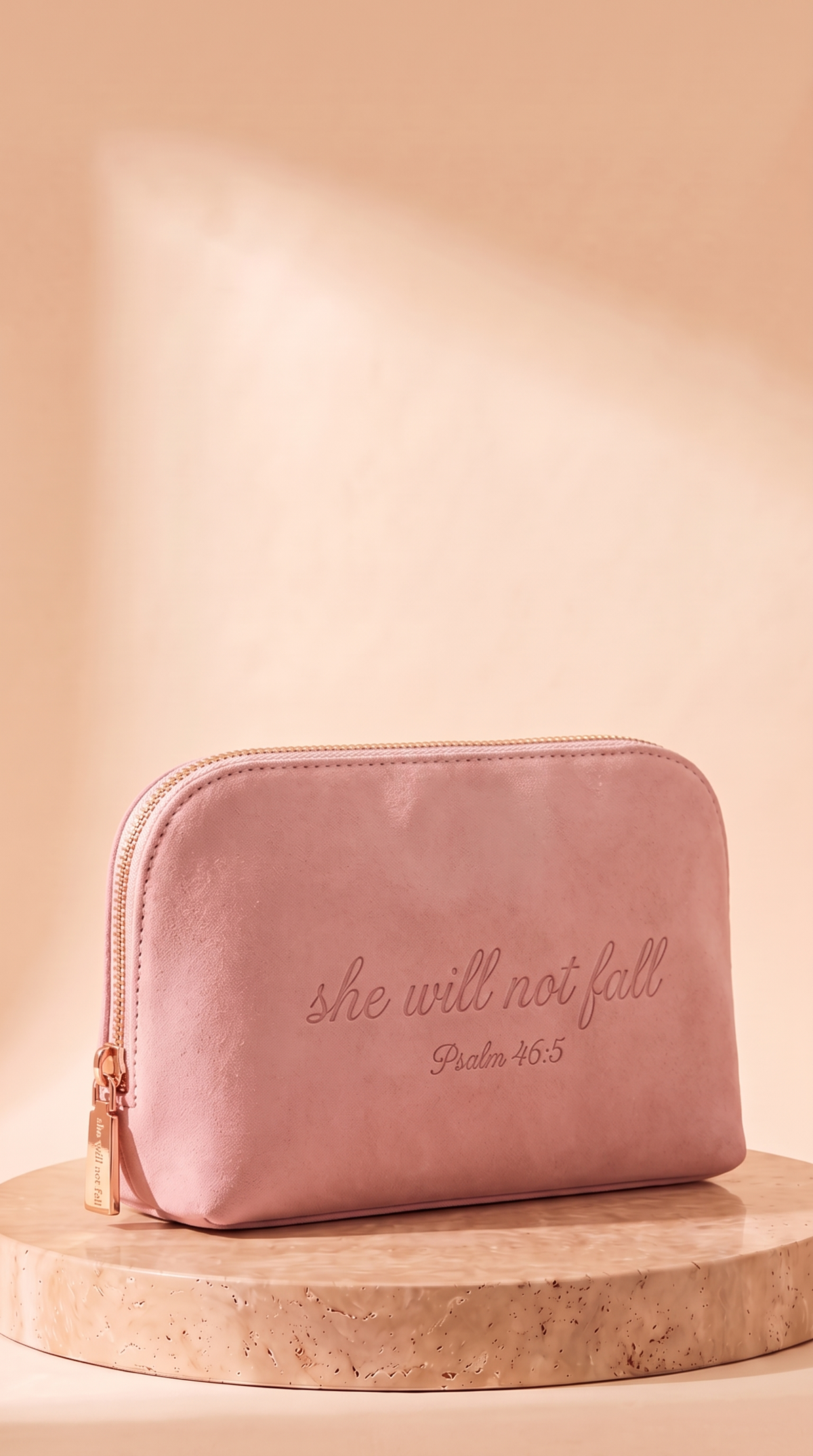 The 46:5 Pouch, a blush-pink makeup pouch debossed with 'she will not fall' and Psalm 46:5