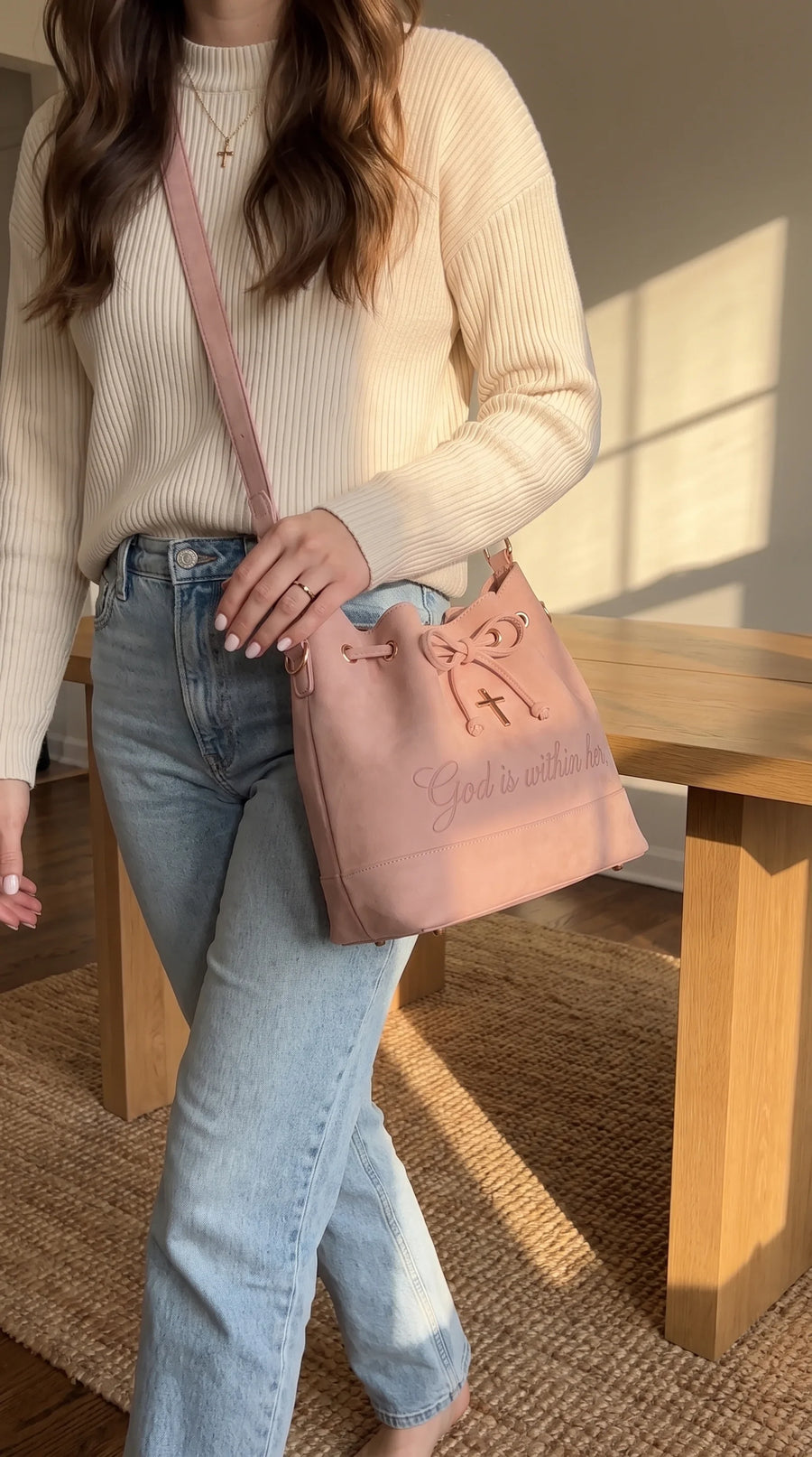 The bag worn crossbody with jeans and a cream sweater